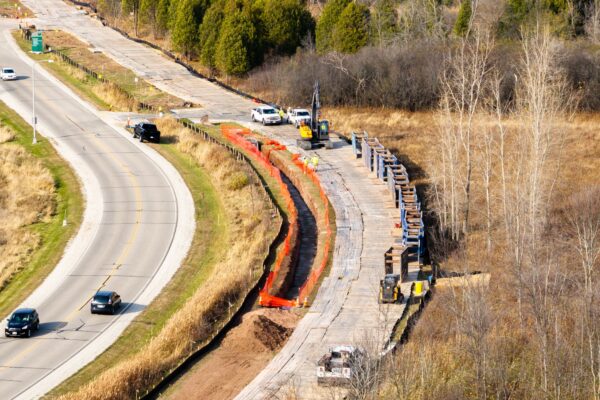 Highway under construction with vehicles, orange barriers, nearby traffic.