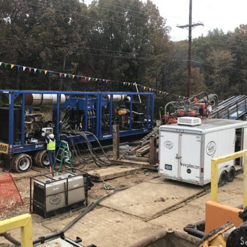 Horizontal directional drilling with machinery, pipes, cables, and trailers operating in Jefferson City, Missouri.