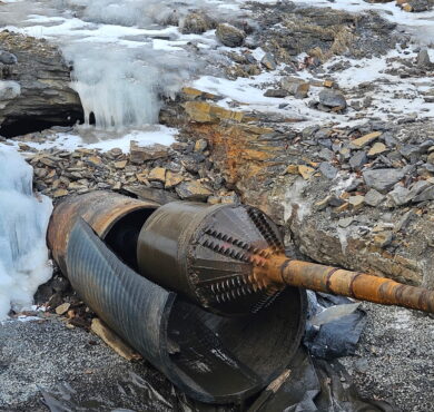 Horizontal directional drill among twisted pipes on icy, rocky ground.