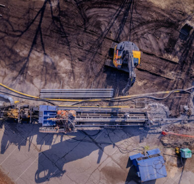 Aerial view of horizontal directional drilling construction site with machinery, pipes, and mud.