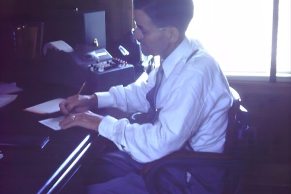 Gabe's founder Jacob Gabrielse wears a white shirt and writes at desk; adding machine behind.