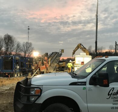 Workers and equipment operate at sunrise with Gabe's truck parked.